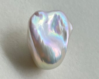 May include: A large, white baroque pearl with iridescent rainbow hues. The pearl has an irregular, organic shape.