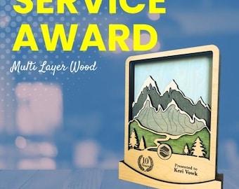 May include: A wooden service award plaque with a multi-layered mountain scene. The plaque has a brown wood frame and a light blue sky with white clouds. The text "Presented to Keri Vowk" is engraved on the plaque. The plaque also has a 10-year anniversary emblem.