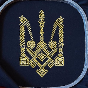 May include: A gold embroidered Ukrainian trident on black fabric in a circular embroidery hoop.