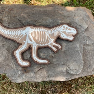 Iron patch with a print of a famous dinosaur Tyrannosaurus rex (T.rex) with bones which are glowing in the dark  7.3” x 4.8”