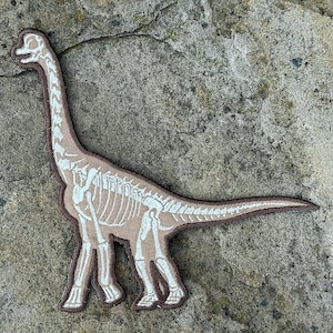 Parche de hierro de dinosaurio Brachiosaurus: Huesos que brillan en la oscuridad (18 x 16,5 cm)