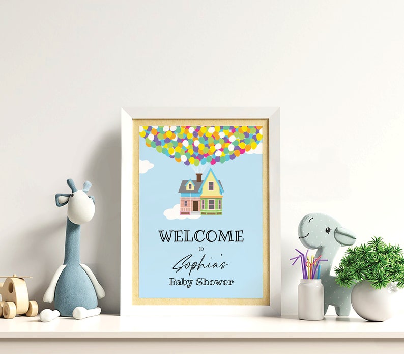 K&ouml;nnte beinhalten: Ein wei&szlig;er Rahmen mit blauem Hintergrund und einem Haus mit Ballons. Der Text lautet "Willkommen zur Babyparty von Sophia".