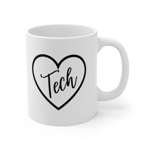 Könnte beinhalten: Weiße Keramik-Kaffeetasse mit einem schwarzen Umriss eines Herzens, in dem "Tech" steht.