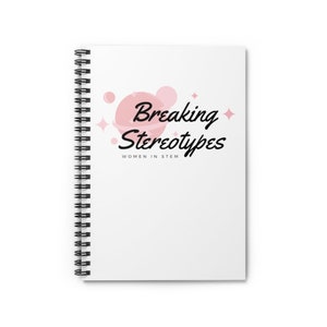 Puede incluir: Una libreta espiral blanca con un gráfico rosa y blanco de un planeta y estrellas. El texto "Breaking Stereotypes" está escrito en letra cursiva negra. Debajo del texto está la frase "Women in STEM" en letra negra más pequeña.