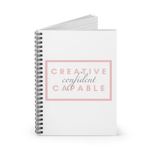 Op de afbeelding: Een wit spiraalnotitieblok met een roze rechthoek met de tekst "CREATIVE confident CAPABLE".