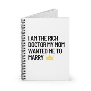 May include: White spiral notebook with the text "I am the rich doctor my mom wanted me to marry" and a gold crown.