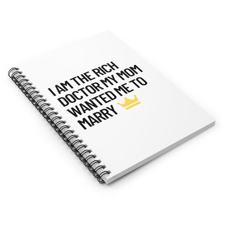 May include: White spiral notebook with black text that reads "I am the rich doctor my mom wanted me to marry" with a gold crown icon.
