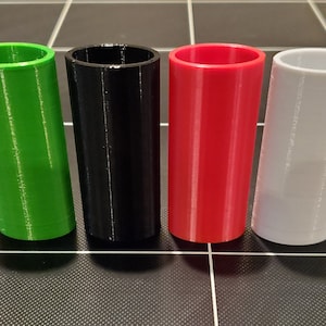 Puede incluir: Cuatro contenedores cilíndricos de plástico en verde, negro, rojo y blanco.