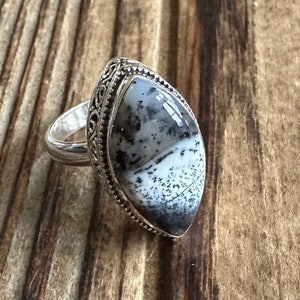 May include: A silver ring with a black and white agate stone set in a filigree design.