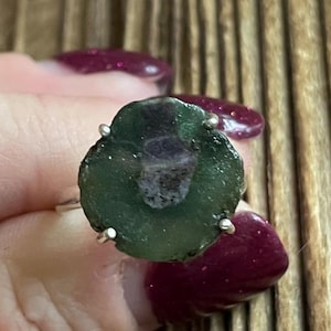 May include: A silver ring with a green and purple gemstone. The gemstone has a swirling pattern and is set in a silver bezel.