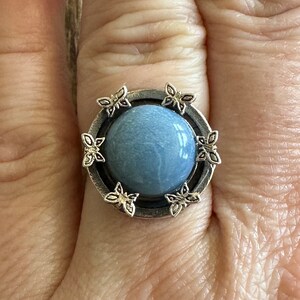 May include: A silver ring with a blue stone surrounded by butterfly designs.