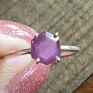 May include: A silver ring with a purple hexagonal gemstone.
