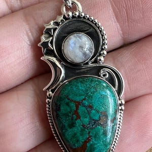 May include: A silver pendant with a green and brown gemstone, a round moonstone, and a star design.