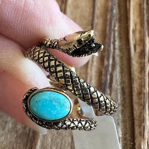 May include: A gold snake ring with a turquoise stone. The snake is coiled around the stone and has a detailed head.