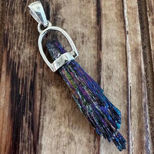 May include: A silver pendant featuring a iridescent black, blue, and purple crystal in a silver horseshoe-shaped bail.