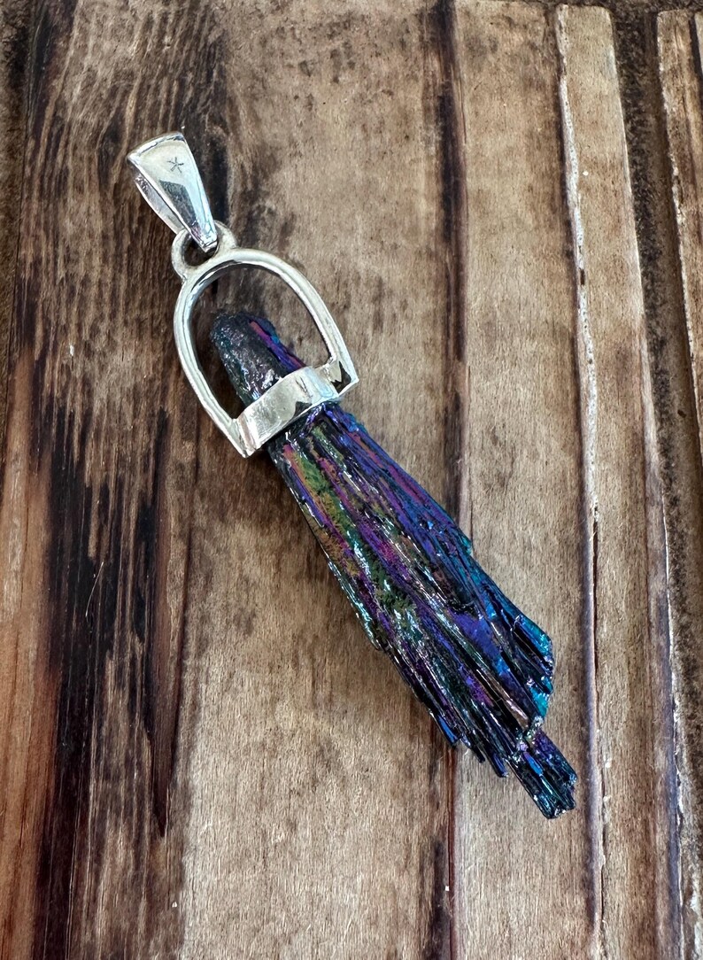 May include: A silver pendant featuring a iridescent black, blue, and purple crystal in a silver horseshoe-shaped bail.