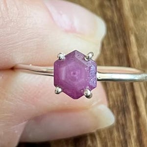May include: A silver ring with a faceted, hexagonal, purple gemstone.