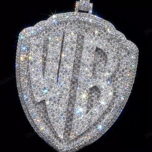 May include: A silver pendant shaped like a shield with a stylized logo made of sparkling white diamonds.