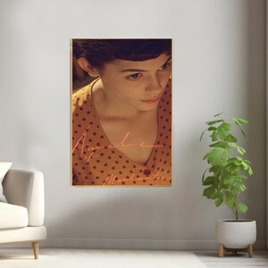 May include: A movie poster featuring a close-up of a woman with short dark hair, wearing a yellow and brown polka dot dress. The text "Am&eacute;lie" is written in pink cursive script.