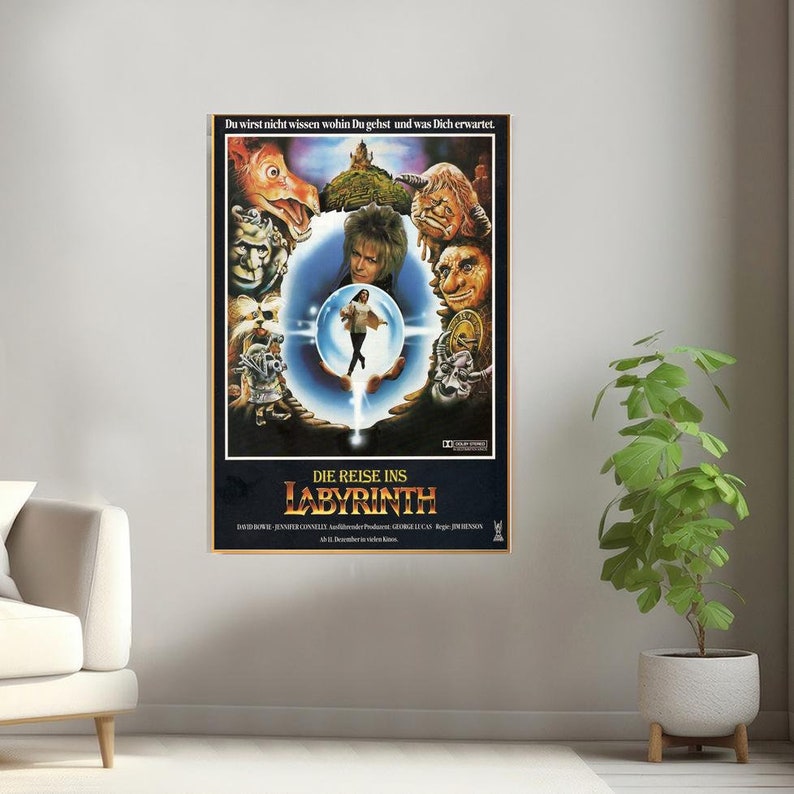 May include: A vintage movie poster for the film Labyrinth, featuring a dark blue background with a circular frame. The frame contains a young woman in a white dress standing on a hand, surrounded by various creatures. The text on the poster reads "Du wirst nicht wissen wohin Du gehst und was Dich erwartet. DIE REISE INS LABYRINTH".