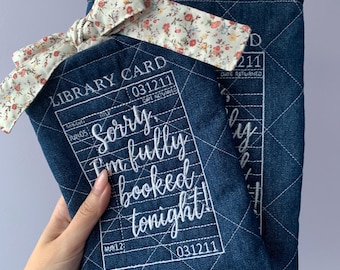 Funda acolchada y bordada de tela vaquera para libros o lectores electrónicos con cierre de lazo floral.
