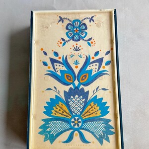 May include: A vintage decorative box with a blue and yellow floral design. The box has a white background and a blue border.