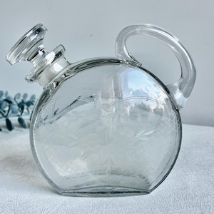 Vintage floral etched round glass decanter with handle and stopper, clear decorative bar bottle with chip, mid-century style