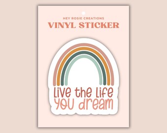 May include: A vinyl sticker on a light pink backing card featuring the text HEY ROSIE CREATIONS VINYL STICKER at the top. The sticker displays a multi-coloured rainbow arch in muted tones of pink, orange, and teal with the text LIVE THE LIFE YOU DREAM.