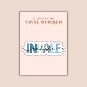 May include: A vinyl sticker on a light pink backing card labeled HEY ROSIE CREATIONS VINYL STICKER. The sticker features the word INHALE in blue and light blue block letters with the word exhale written in black cursive script across it.