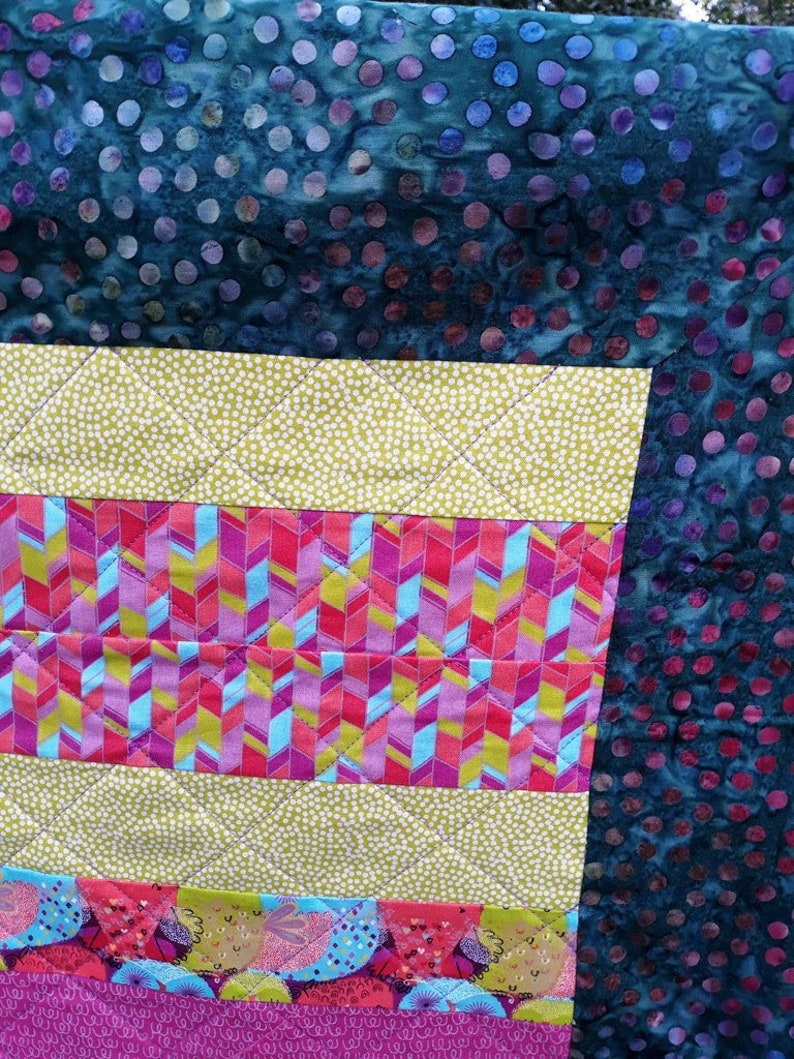 以下が含まれることがあります： 様々なカラフルな生地を使ったパッチワークのデザインのキルト。キルトは、水玉模様、ストライプ、幾何学模様など、さまざまなパターンで構成されています。キルトは、鮮やかでカラフルな芸術作品です。