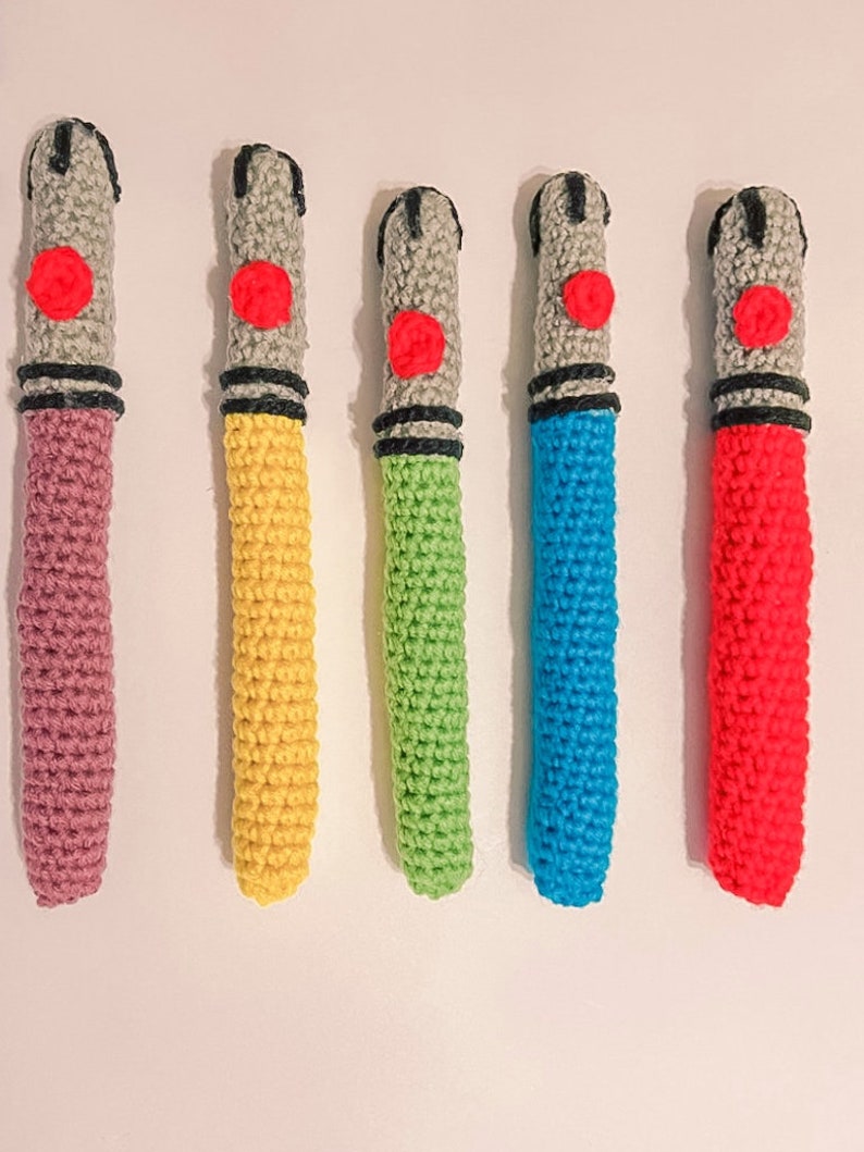K&ouml;nnte beinhalten: F&uuml;nf handgefertigte H&auml;kel-Lichtschwerter in verschiedenen Farben. Jedes hat einen grauen Griff mit einem roten Knopf, ein schwarzes Band und eine farbige Klinge. Zu den Farben geh&ouml;ren Rosa, Gelb, Gr&uuml;n, Blau und Rot. Die Lichtschwerter sind vertikal angeordnet.