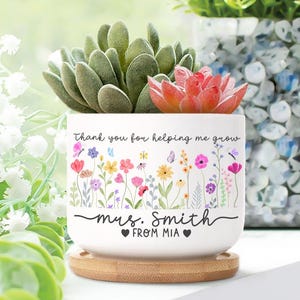 May include: A white ceramic planter with a floral design and the text "Thank you for helping me grow" and "Mrs. Smith from Mia". The planter holds a succulent plant and sits on a bamboo saucer.