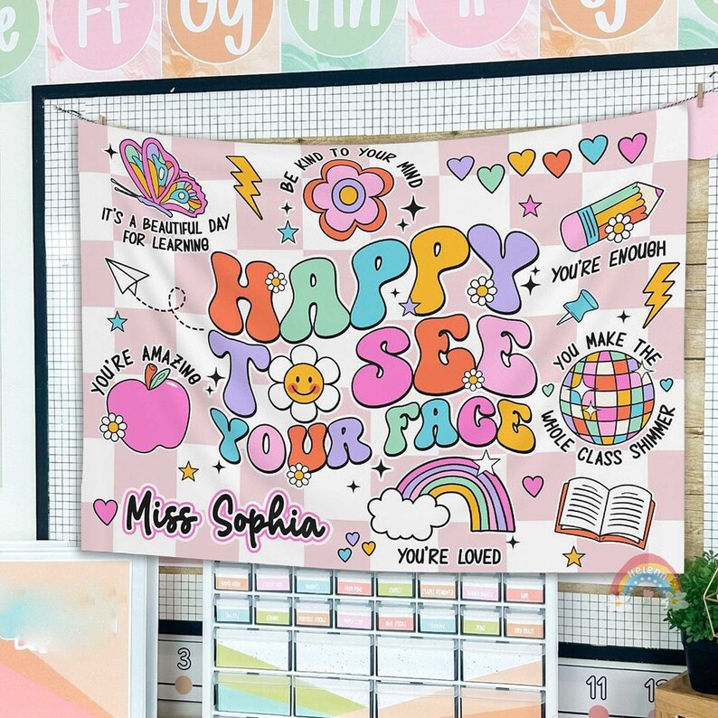 Peut inclure: Une banni&egrave;re de classe &agrave; carreaux rose et blancs avec le texte "Happy to See Your Face" en lettres color&eacute;es de style r&eacute;tro. La banni&egrave;re pr&eacute;sente &eacute;galement diverses illustrations, notamment un arc-en-ciel, une boule disco, un livre, une fleur, une pomme et un papillon. Le texte "Miss Sophia" est en bas de la banni&egrave;re.