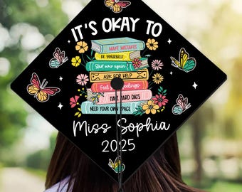 May include: Black graduation cap with a stack of colorful books and butterflies. The text "IT'S OKAY TO" is at the top, followed by a list of affirmations. The name "Miss Sophia" and the year "2025" are at the bottom.