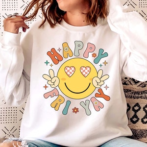 May include: White sweatshirt with a colorful graphic of a smiley face with heart-shaped eyes and the text "HAPPY FRIDAY" in a retro font.