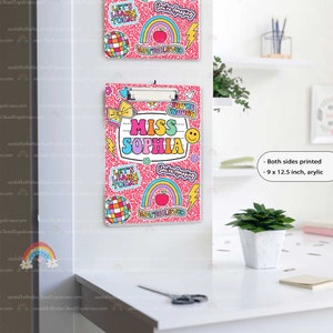 Puede incluir: Un portapapeles de acr&iacute;lico de 22,86 x 31,75 cm con fondo rosa moteado y pegatinas coloridas que incluyen arco&iacute;ris, bolas de discoteca, rayos y caras sonrientes. El texto dice MISS SOPHIA, YOU'RE ENOUGH, YOU'RE AMAZING, YOU'RE LOVED y LET'S LEARN TODAY.