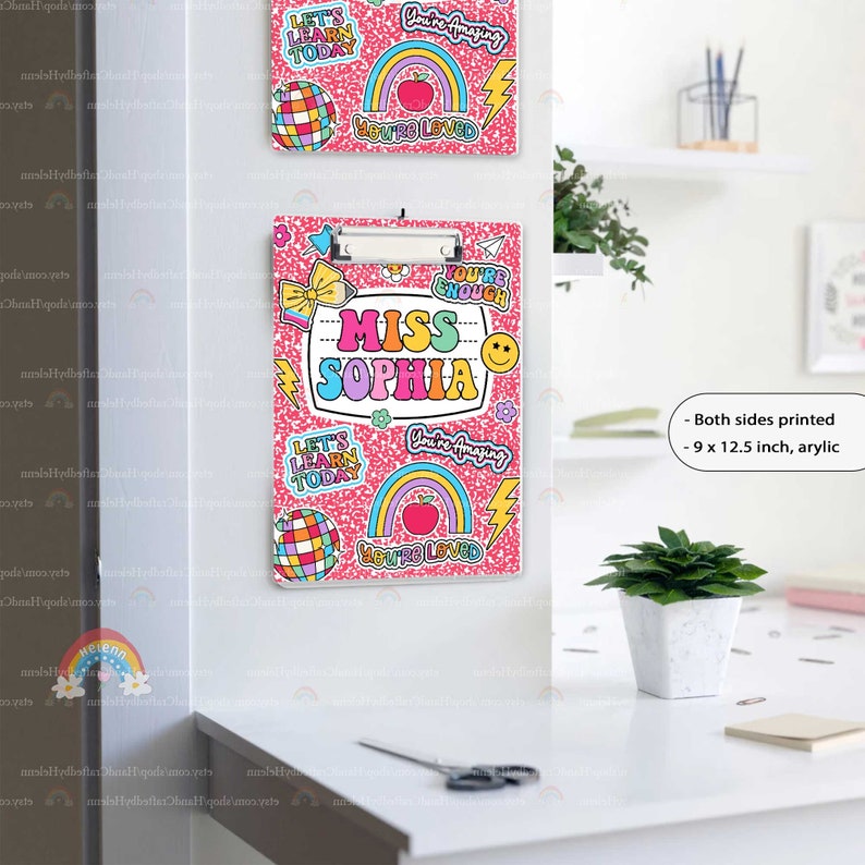 Puede incluir: Un portapapeles de acr&iacute;lico de 22,86 x 31,75 cm con fondo rosa moteado y pegatinas coloridas que incluyen arco&iacute;ris, bolas de discoteca, rayos y caras sonrientes. El texto dice MISS SOPHIA, YOU'RE ENOUGH, YOU'RE AMAZING, YOU'RE LOVED y LET'S LEARN TODAY.