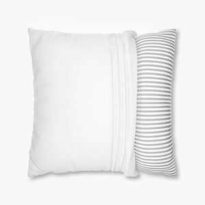 May include: Two pillows. A large, square white pillow with a pleated edge is next to a long, cylindrical pillow with gray and white horizontal stripes. The pillows are on a white background.