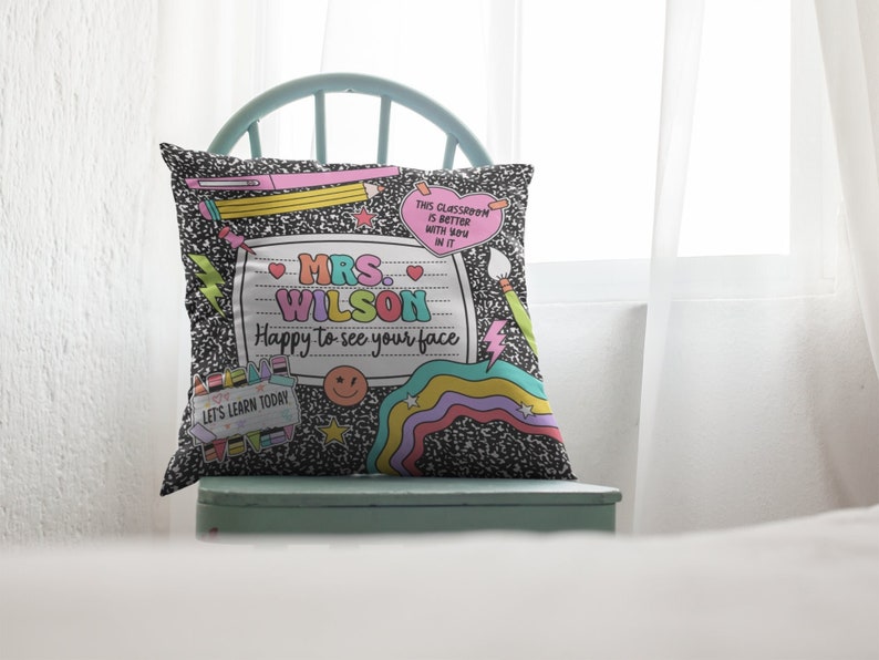 May include: A decorative throw pillow with a notebook paper design. The pillow features the text "MRS. WILSON Happy to see your face" and other school-themed graphics. The background is a black and white composition notebook pattern.
