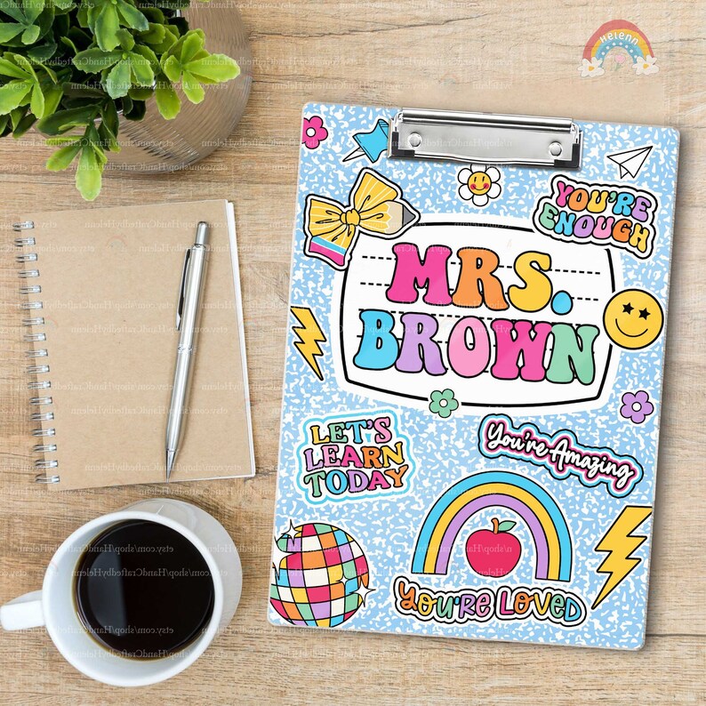 Puede incluir: Un portapapeles azul claro con un patr&oacute;n de motas blancas y pegatinas coloridas, incluyendo un arco&iacute;ris, una manzana, una bola de discoteca y el texto Mrs. Brown, You're Enough, Let's Learn Today, You're Amazing y You're Loved.