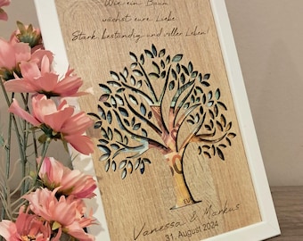 May include: A white framed wooden plaque with a cutout tree design. The tree is filled with euro bills. The plaque has the text "Wie ein Baum wächst eure Liebe Stark, beständig und voller Leben!" and "Vanessa & Markus 31. August 2024".