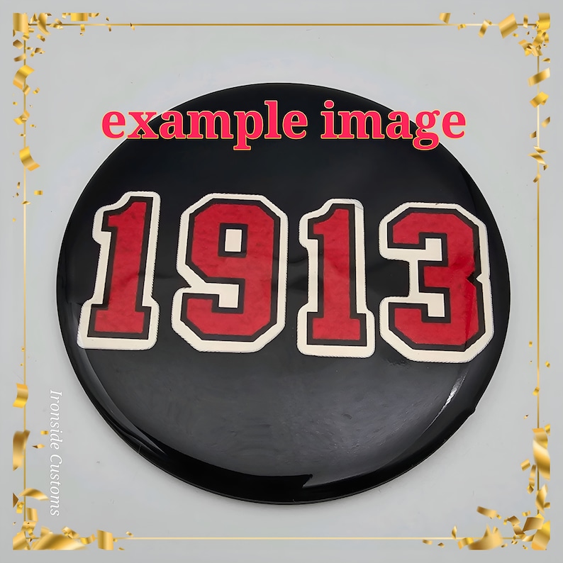 K&ouml;nnte beinhalten: Schwarzer runder Knopf mit wei&szlig;em Rand und roten Zahlen "1913" in einer Vintage-Schriftart.