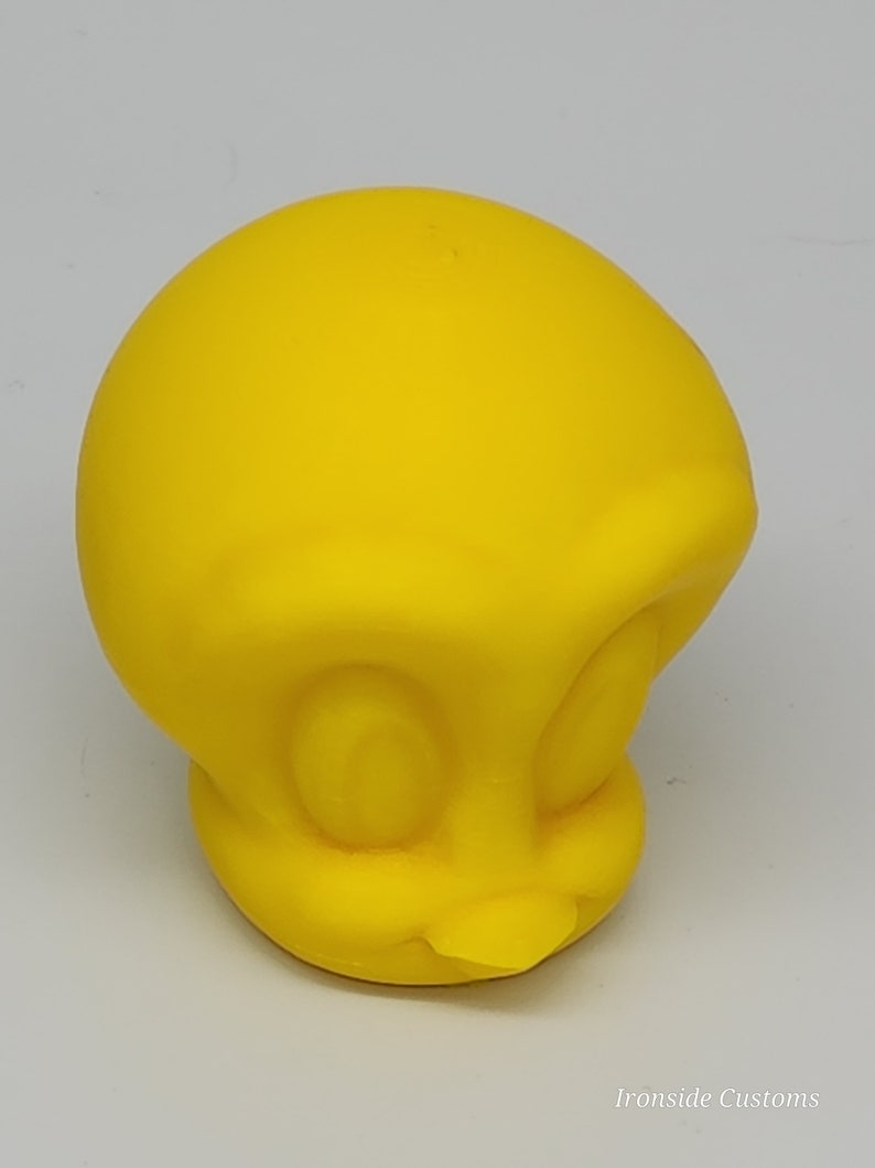 Op de afbeelding: Een felgele, driedimensionale figuur van het tekenfilmfiguur Tweety. De figuur heeft grote, ronde ogen, een kleine snavel en een afgerond hoofd. De figuur is gemaakt van een glad materiaal en staat tegen een effen achtergrond.