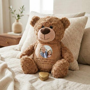 Pode incluir: Um urso de peluche castanho com um remendo circular bege no peito com uma fotografia impressa de um adulto e uma criança. O remendo inclui o texto: Hold me close when you need a hug, I'm always with you! Love you Forever xxx.