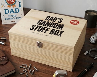May include: A rectangular light-colored wooden storage box with a metal latch. The lid features the black text "DAD'S RANDOM STUFF BOX" and "LOVE ALWAYS LILY & FLORENCE" with a small red "DO NOT ENTER" sticker on the top right corner.