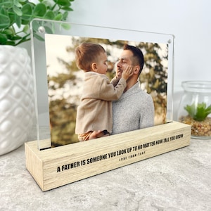 May include: A wooden photo frame with a clear acrylic insert. The frame features a photo of a father and son, with the inscription "A father is someone you look up to no matter how tall you grow. Love from Toby."