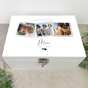 May include: White wooden keepsake box with a silver clasp. The lid features three framed photos and the words "MEMORIES OF YOU." Below the photos, the word "Mum" is written in cursive, along with the years 1962-2026 and two heart symbols.