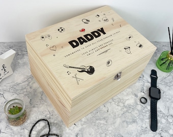 May include: A rectangular light-colored wooden box with a metal latch. The lid features the text DADDY, SOMEWHERE TO KEEP ALL YOUR RANDOM THINGS, LOVE ALWAYS AND FOREVER, EMILY AND ETHAN XXX, surrounded by black line art icons of a guitar, soccer ball, headphones, and other symbols.