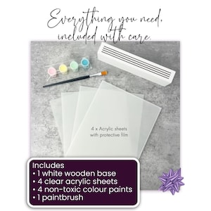 May include: A craft kit with a white wooden base, four clear acrylic sheets, four non-toxic color paints, and a paintbrush. The kit includes a white rectangular object, a paintbrush, and small containers of pink, yellow, green, and blue paint. Text reads "Everything you need, included with care."