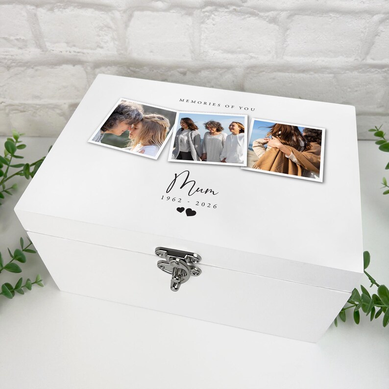 May include: A white wooden keepsake box with a silver clasp. The lid features three framed photos and the text "MEMORIES OF YOU" above the word "Mum" and the years 1962-2026, with two heart symbols below.